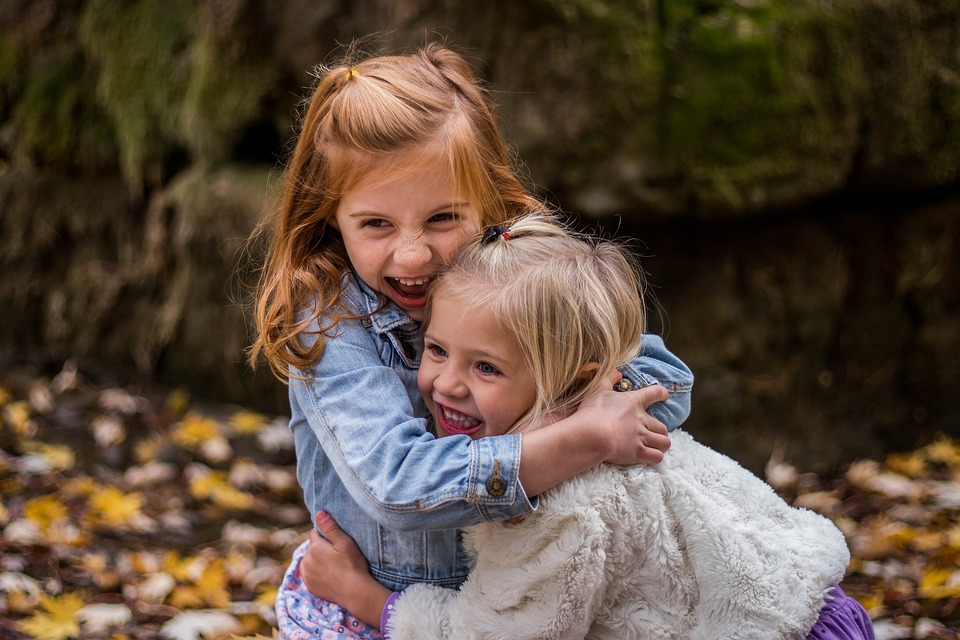 dos niñas abrazándose mientras sonríen
