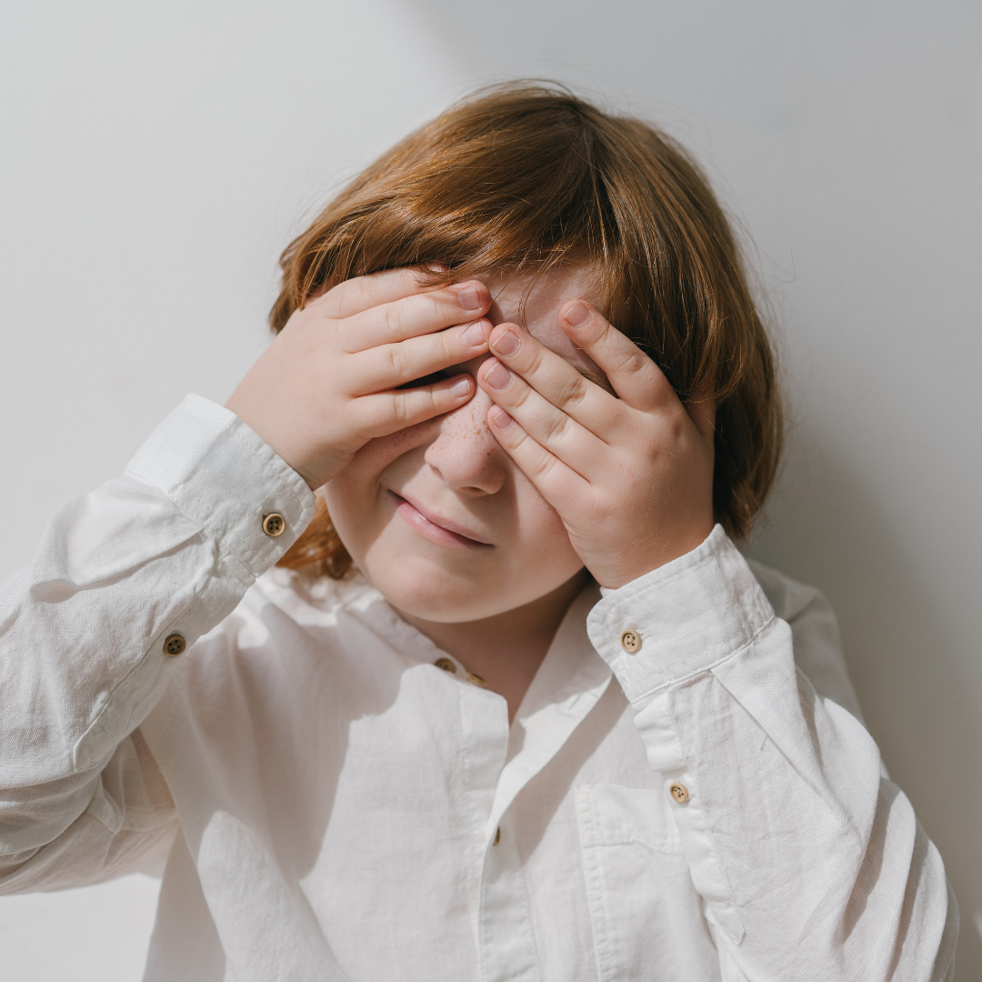 un niño tapándose los ojos con las dos manos. imagen que busca reflejar las dificultades que hay para diferenciar TDAH y TEA